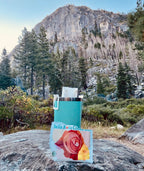 Bella Rosa Coffee Co. packet with blue insulated tumbler in a scenic outdoor setting.